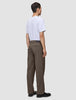 Ein Mann, von hinten gesehen, der ein weißes T-Shirt und eine Atelier Pants Relaxed in Dunkelbeige aus schwerem Broken-Twill trägt.