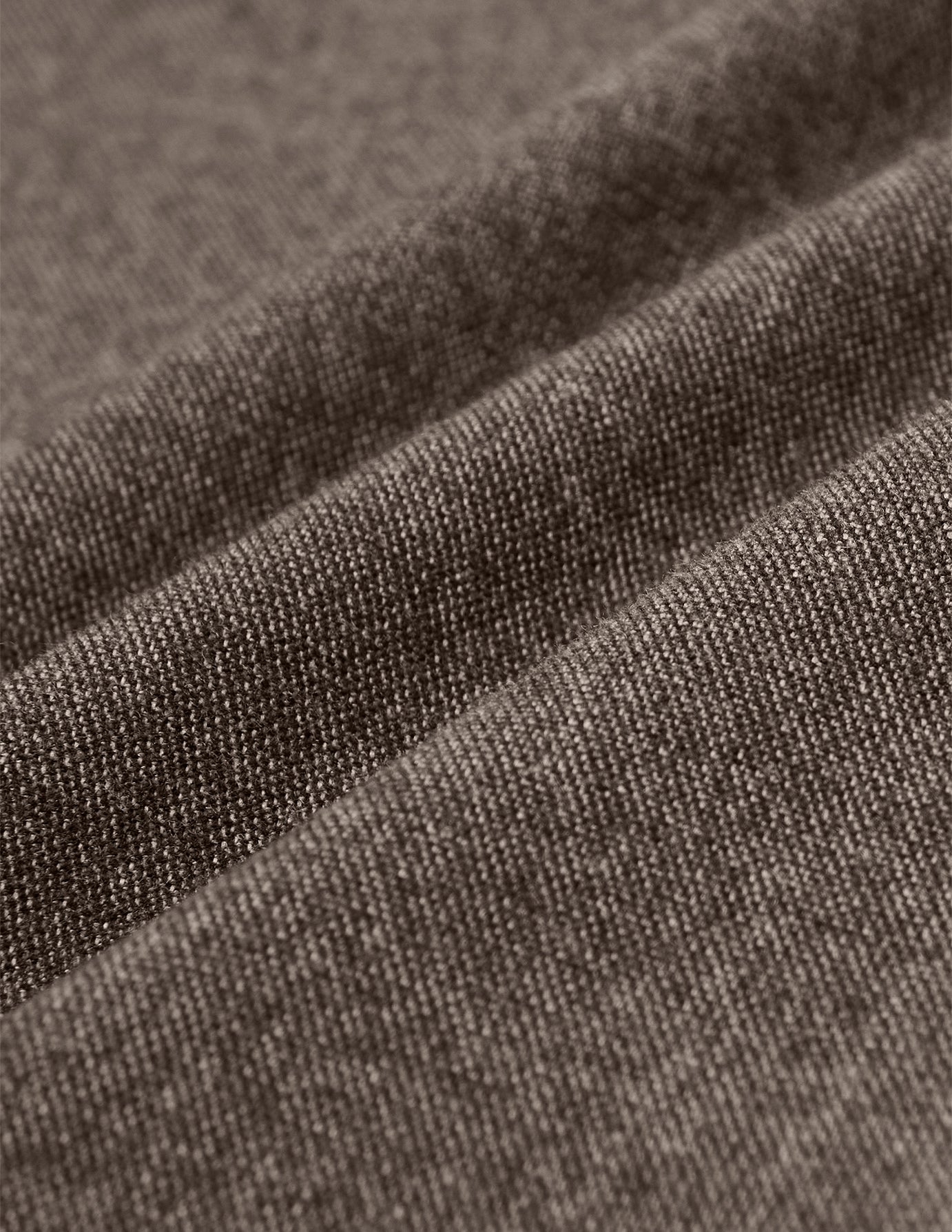 Nahaufnahme der dunkelbeigen Atelier Pants Relaxed Dark Beige aus schwerem, gebrochenem Twill mit weichen, diagonalen Falten, die für skandinavisches Design charakteristisch sind.