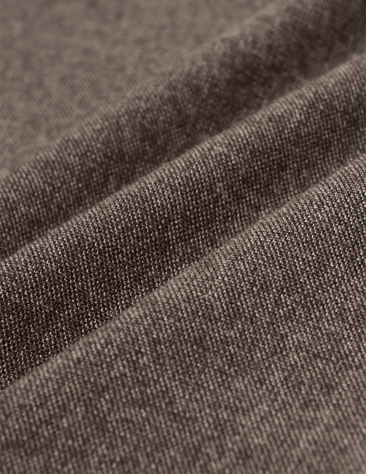 Nahaufnahme der dunkelbeigen Atelier Pants Relaxed Dark Beige aus schwerem, gebrochenem Twill mit weichen, diagonalen Falten, die für skandinavisches Design charakteristisch sind.