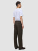 Eine Person, von hinten gesehen, die ein weißes T-Shirt und eine Atelier Pants Relaxed in Dunkelbraun aus schwerem, gebrochenem Twill trägt.