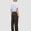 Eine Person, von hinten gesehen, die ein weißes T-Shirt und eine Atelier Pants Relaxed in Dunkelbraun aus schwerem, gebrochenem Twill trägt.