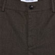 Nahaufnahme der Atelier Pants Relaxed in Dunkelbraun aus schwerem, gebrochenem Twill mit Knopfverschluss und Markenetikett am Bund.