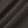 Nahaufnahme der Atelier Pants Relaxed Dark Brown aus gefaltetem, dunkelbraunem, schwerem Broken-Twill-Stoff mit strukturierter, gesprenkelter Webung und einem lässigen Schnitt.