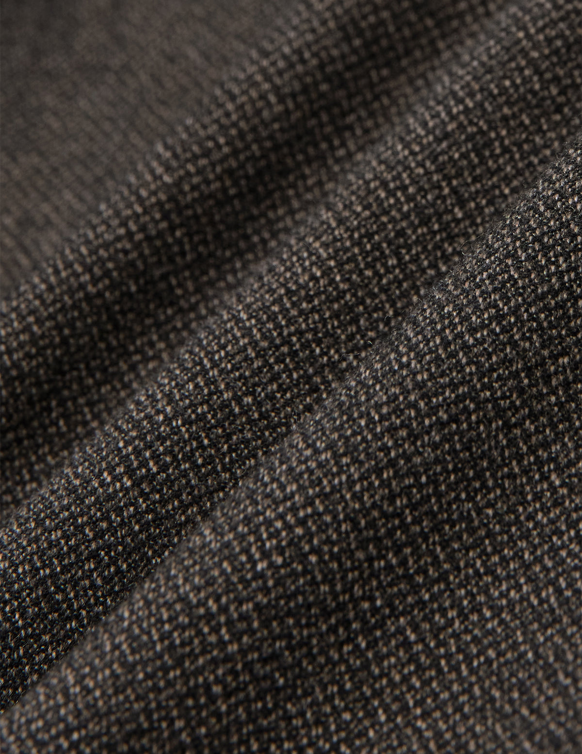 Nahaufnahme der Atelier Pants Relaxed Dark Brown aus gefaltetem, dunkelbraunem, schwerem Broken-Twill-Stoff mit strukturierter, gesprenkelter Webung und einem lässigen Schnitt.