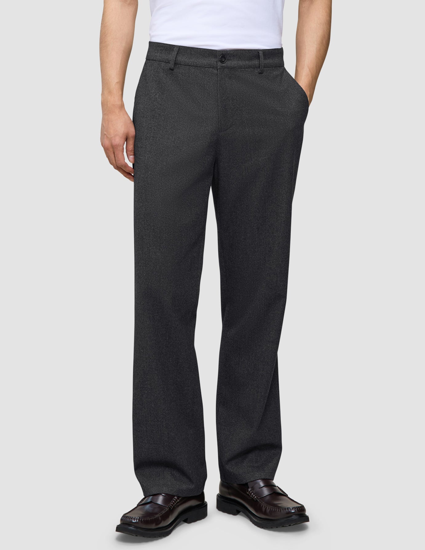 Eine Person trägt eine Atelier Pants Relaxed in Dunkelgrau aus schwerem Broken-Twill und dunkelbraune Loafer.