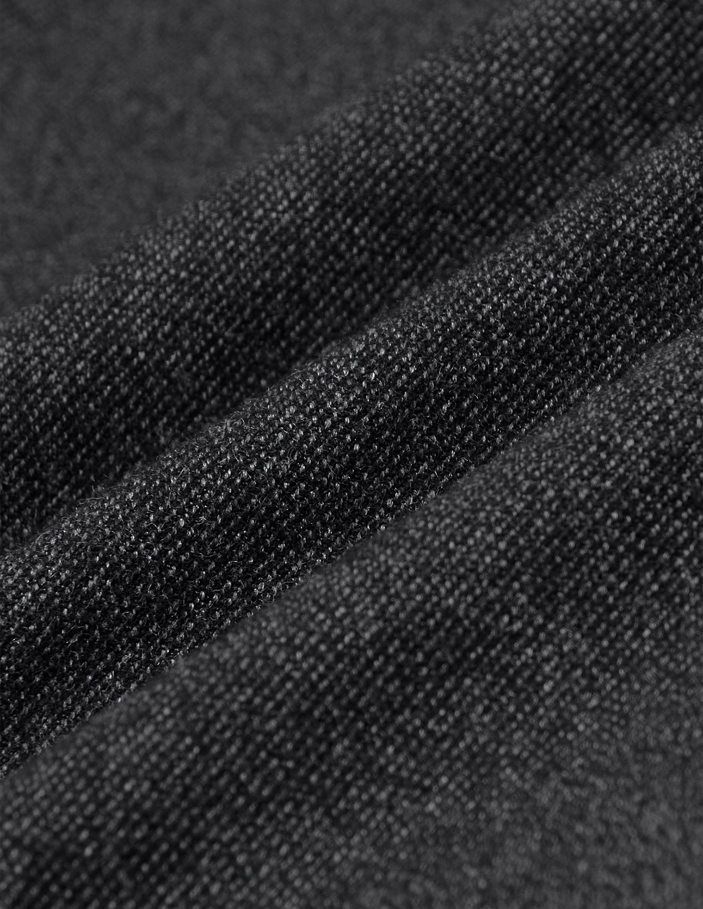 Nahaufnahme der gefalteten Atelier Pants Relaxed in Dunkelgrau aus einem schweren, gebrochenen Twill mit sichtbarer Strickstruktur.
