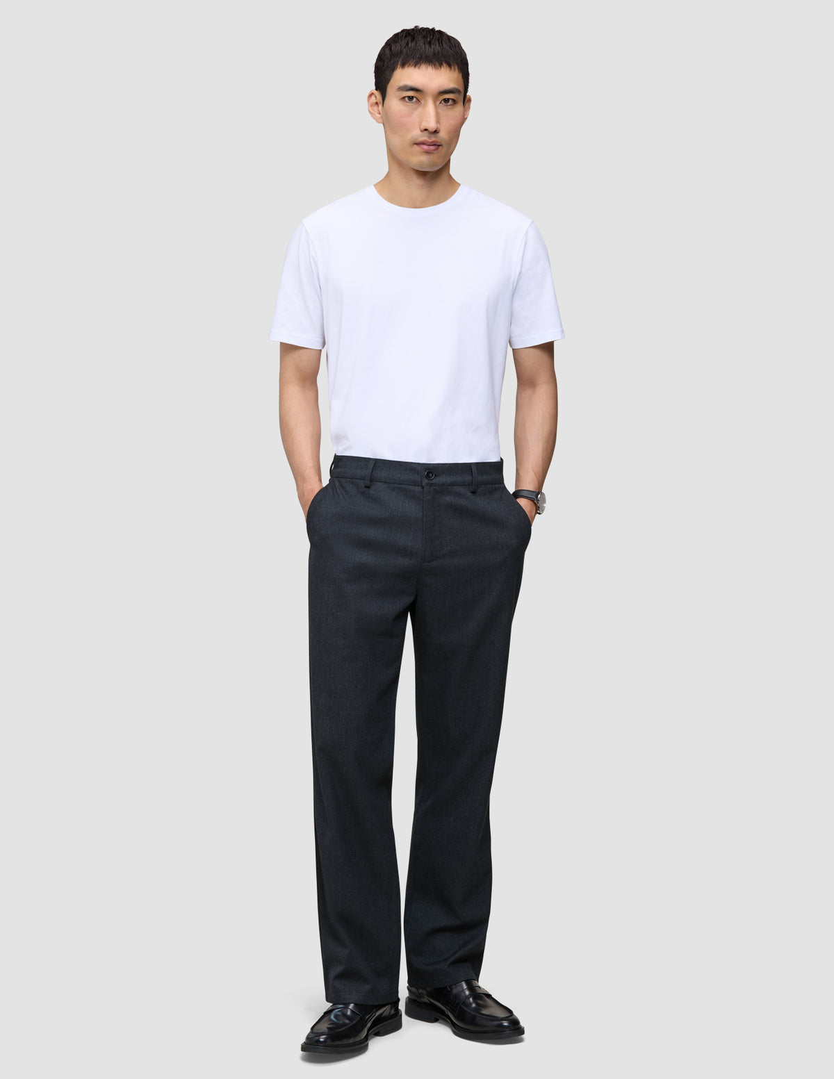 Ein Mann, der ein weißes T-Shirt mit Rundhalsausschnitt und eine Atelier Pants Relaxed Dark Navy aus schwerem, gebrochenem Twill trägt.