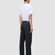Ein Mann, von hinten gesehen, der ein weißes T-Shirt und eine Atelier Pants Relaxed Dark Navy aus schwerem, gebrochenem Twill trägt.