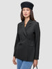 Eine Person, die einen schwarzen, zweireihigen Avira Blazer Black-Damenblazer und eine schwarze Baskenmütze im skandinavischen Stil trägt.