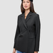 Eine Person, die einen schwarzen, zweireihigen Avira Blazer Black-Damenblazer und eine schwarze Baskenmütze im skandinavischen Stil trägt.