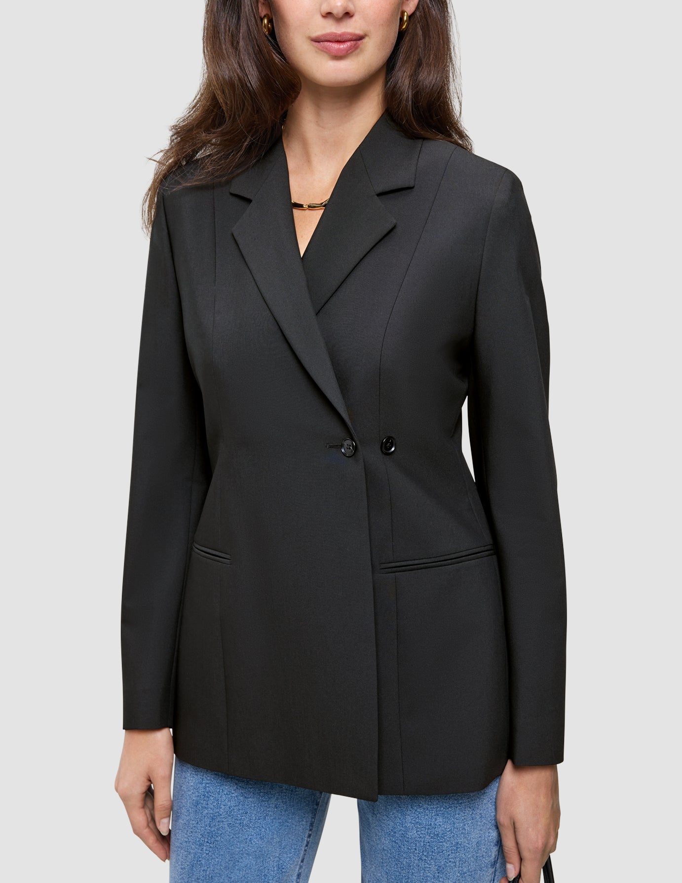 Eine Frau, die einen schwarzen Women’s Avira Blazer Black mit spitz zulaufendem Revers und eine blaue Jeans trägt, die das skandinavische Design zur Geltung bringen.