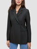 Eine Frau, die einen schwarzen Women’s Avira Blazer Black mit spitz zulaufendem Revers und eine blaue Jeans trägt, die das skandinavische Design zur Geltung bringen.