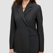Eine Frau, die einen schwarzen Women’s Avira Blazer Black mit spitz zulaufendem Revers und eine blaue Jeans trägt, die das skandinavische Design zur Geltung bringen.