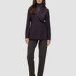 Eine Person, die einen Avira-Blazer für Damen in der Farbe Burgundy Berry im skandinavischen Zweireiher-Design über einem grauen Rollkragenpullover und einer dunklen Hose trägt.