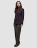 Eine Frau trägt einen burgunderroten Avira-Damenblazer in der Farbe Burgundy Berry im skandinavischen Zweireiher-Design über einem grauen Rollkragenpullover und einer dunklen Hose.