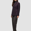 Eine Frau trägt einen burgunderroten Avira-Damenblazer in der Farbe Burgundy Berry im skandinavischen Zweireiher-Design über einem grauen Rollkragenpullover und einer dunklen Hose.
