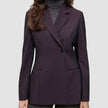 Eine Frau trägt einen dunkelvioletten Women’s Avira Blazer Burgundy Berry im klassischen skandinavischen Zweireiher-Design über einem grauen Rollkragenpullover.