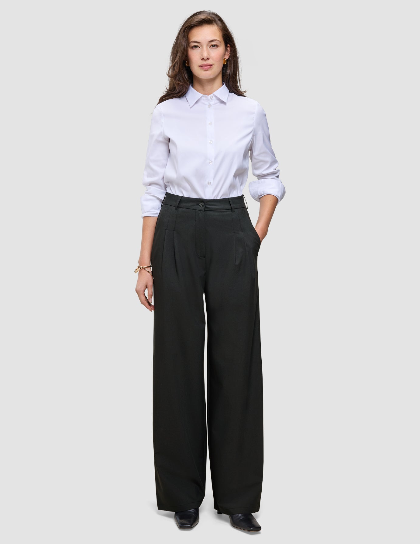 Eine Person, die ein weißes Hemd trägt, das in eine schwarze Damenhose Avira Pants Wide Black gesteckt ist.