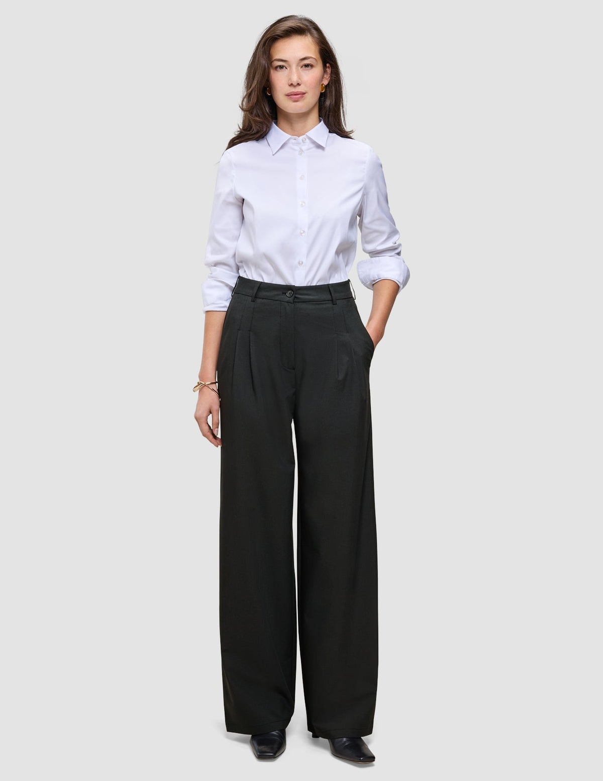 Eine Person, die ein weißes Hemd trägt, das in eine schwarze Damenhose Avira Pants Wide Black gesteckt ist.