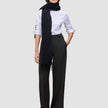 Eine Frau, die ein weißes Hemd, einen schwarzen Schal und die Damenhose Avira Pants Wide Black trägt.