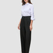 Eine Frau, die ein weißes Hemd trägt, das in eine schwarze Damenhose Avira Pants Wide mit hoher Taille gesteckt ist.