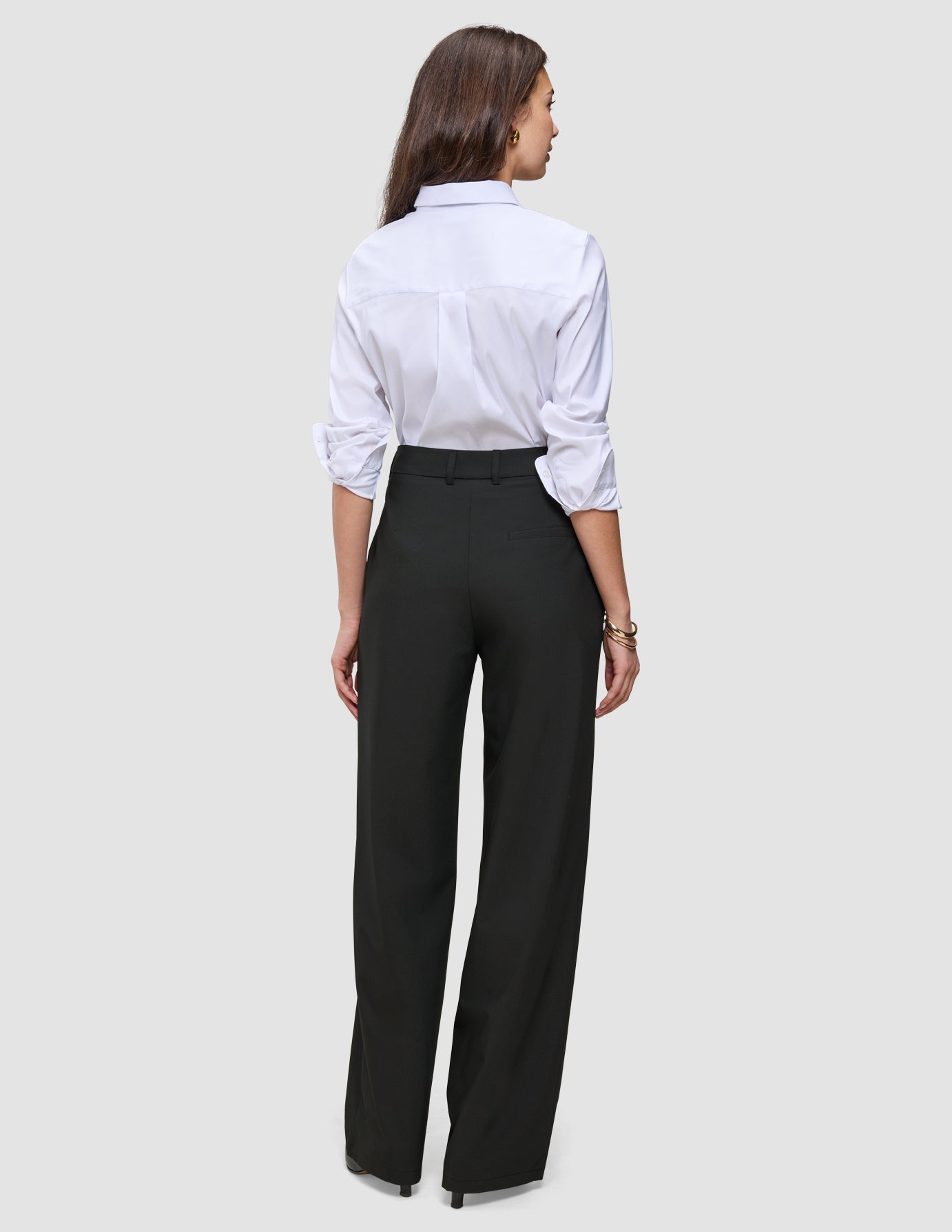 Eine Frau, von hinten gesehen, die ein weißes Hemd und eine schwarze Avira Pants Wide Black für Damen trägt.
