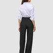 Eine Frau, von hinten gesehen, die ein weißes Hemd und eine schwarze Avira Pants Wide Black für Damen trägt.