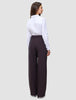 Eine Frau, von hinten gesehen, die ein weißes Hemd trägt, das in die Damenhose Avira Pants Wide in der Farbe Burgundy Berry gesteckt ist.