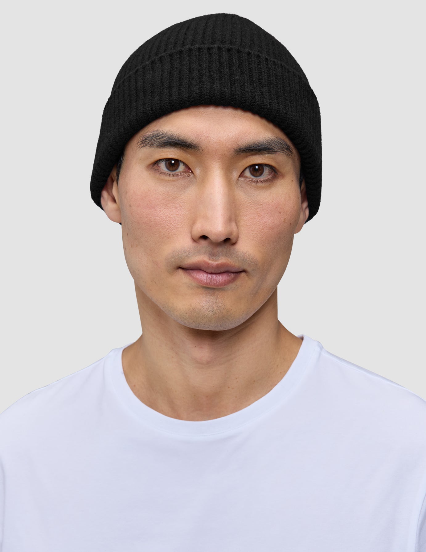Eine Person, die eine schwarze Mütze im minimalistischen skandinavischen Design aus Rippstrick trägt.