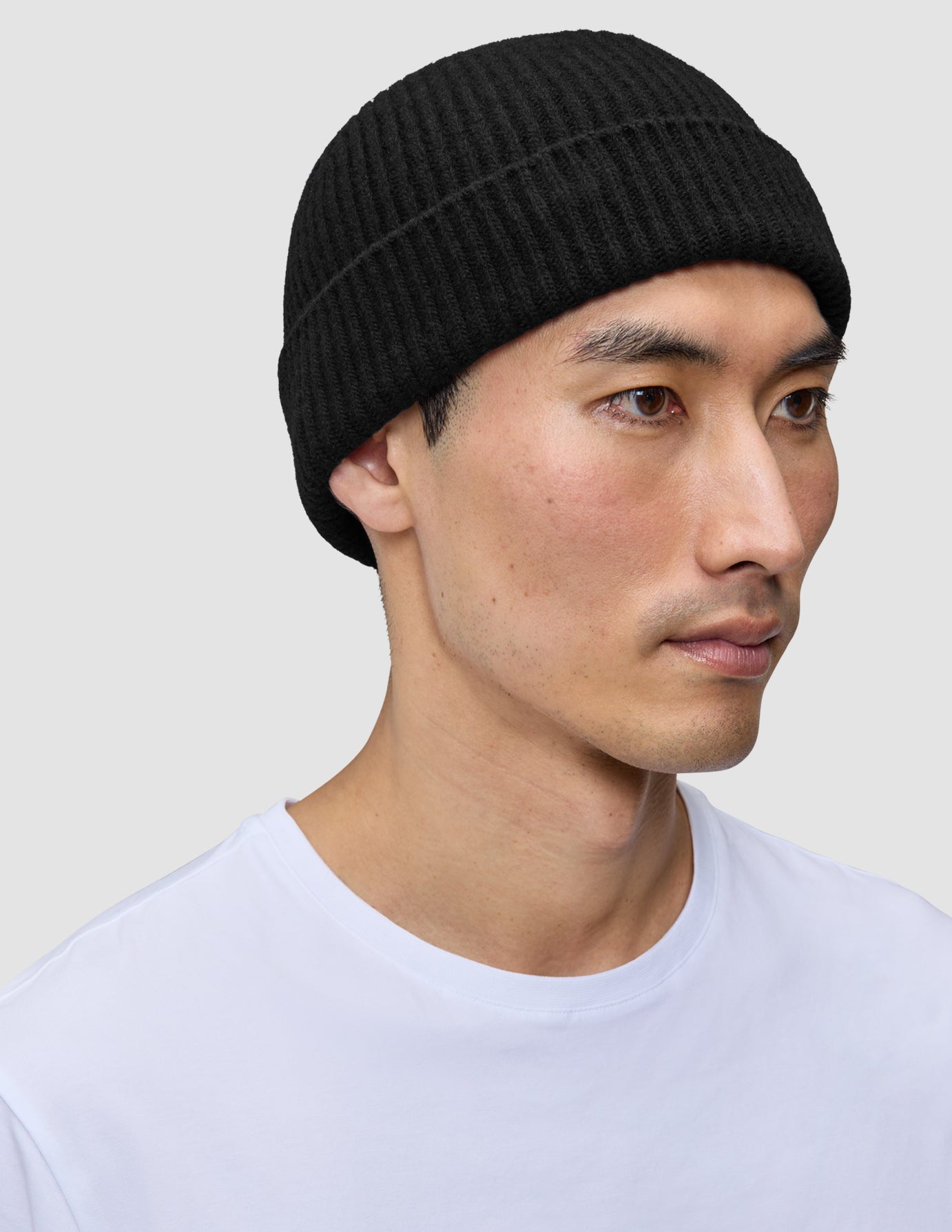 Eine Person, die eine schwarze Mütze mit geripptem Strick und minimalistischem skandinavischem Design trägt.