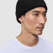 Eine Person, die eine schwarze Mütze mit geripptem Strick und minimalistischem skandinavischem Design trägt.