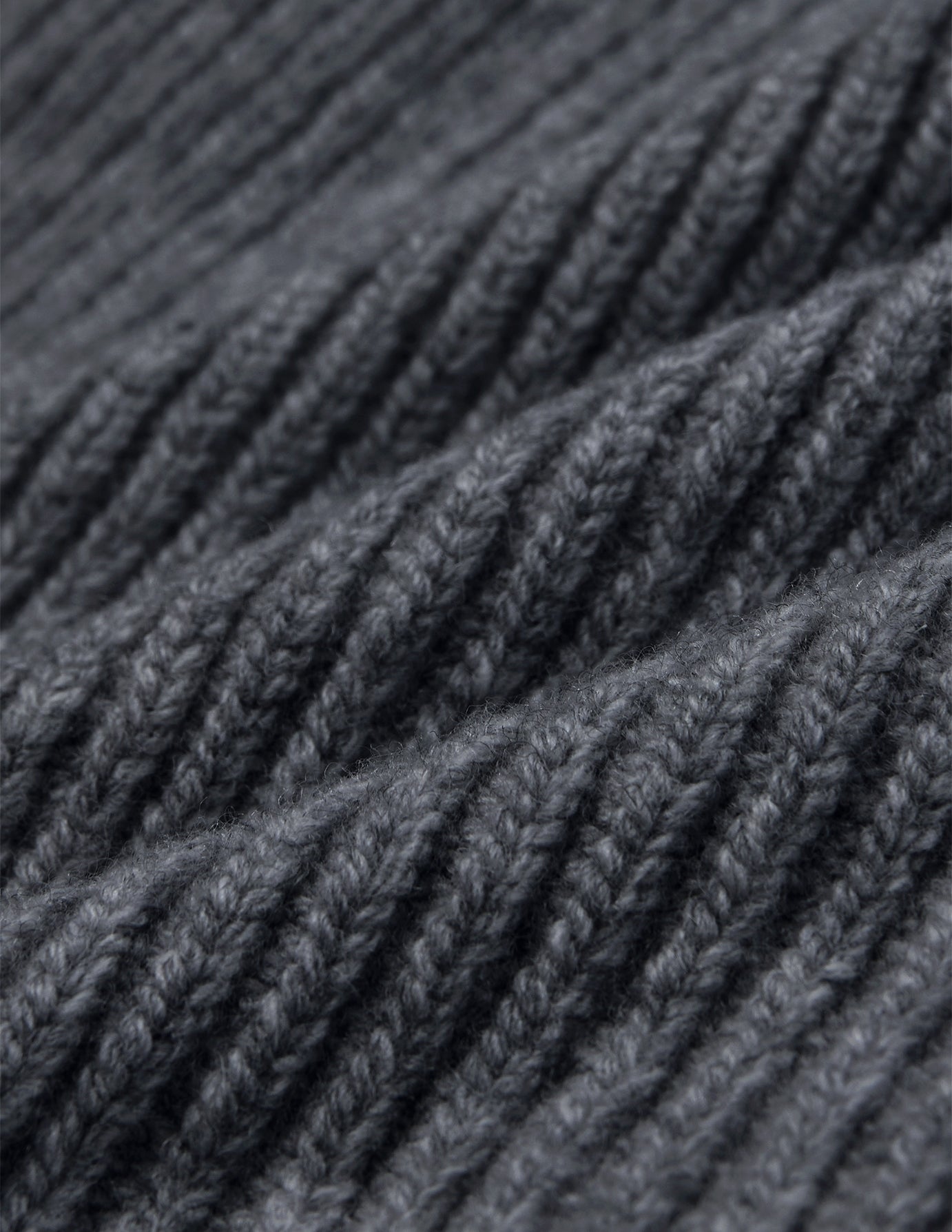 Nahaufnahme einer Mütze Beanie Dark Grey aus dunkelgrauer Merino-Schurwolle mit geripptem Strickmuster.