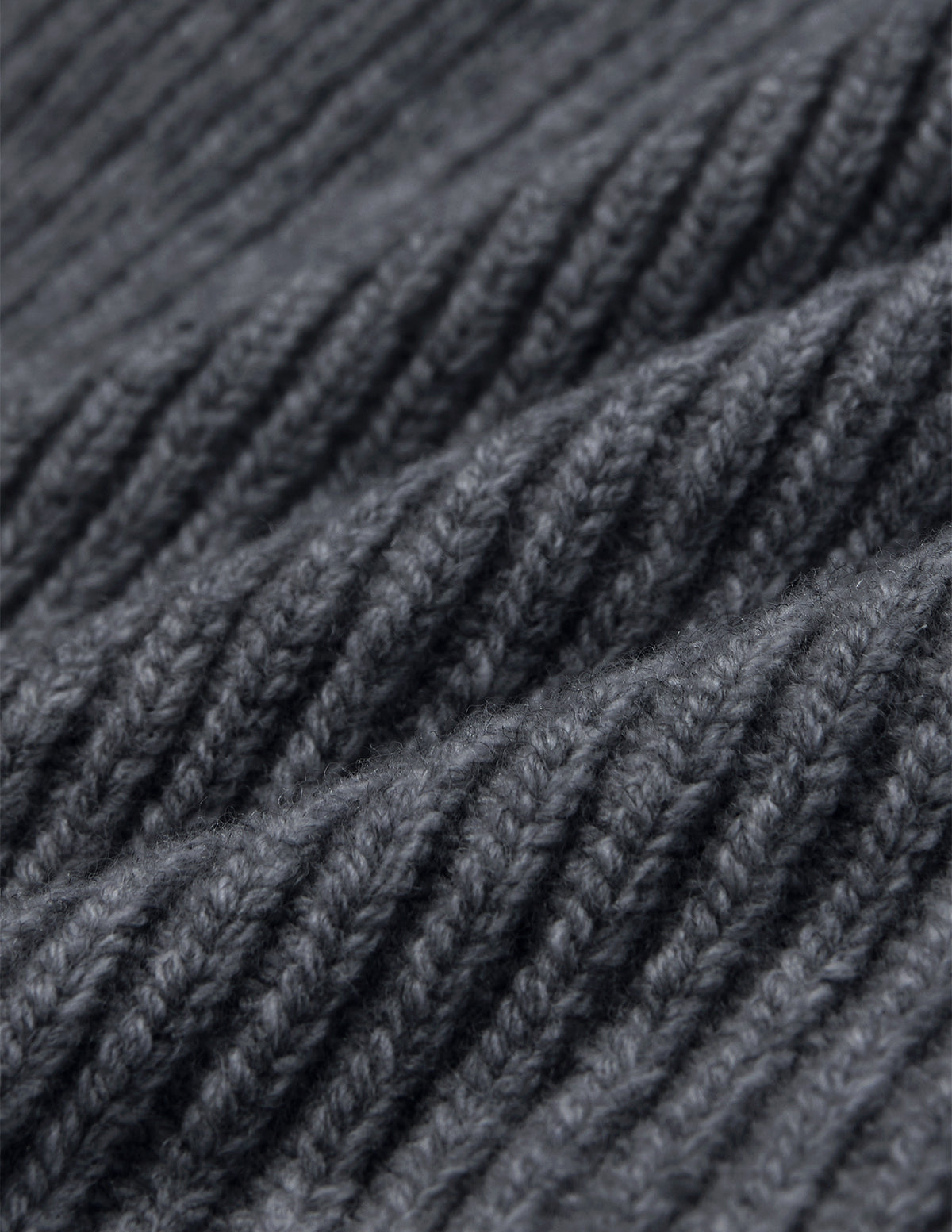 Nahaufnahme einer Mütze Beanie Dark Grey aus dunkelgrauer Merino-Schurwolle mit geripptem Strickmuster.