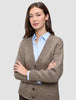 Eine Frau, die eine Damen-Strickjacke aus weicher, grobstrickiger Wolle in Taupe-Melange über einem hellblauen Hemd mit Kragen trägt.