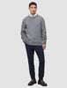 Ein Mann, der einen dicken, weichen Wollpullover mit Rundhalsausschnitt in der Farbe Glacier Grey über einem weißen Hemd mit Kragen, einer dunklen Hose und Loafern trägt.