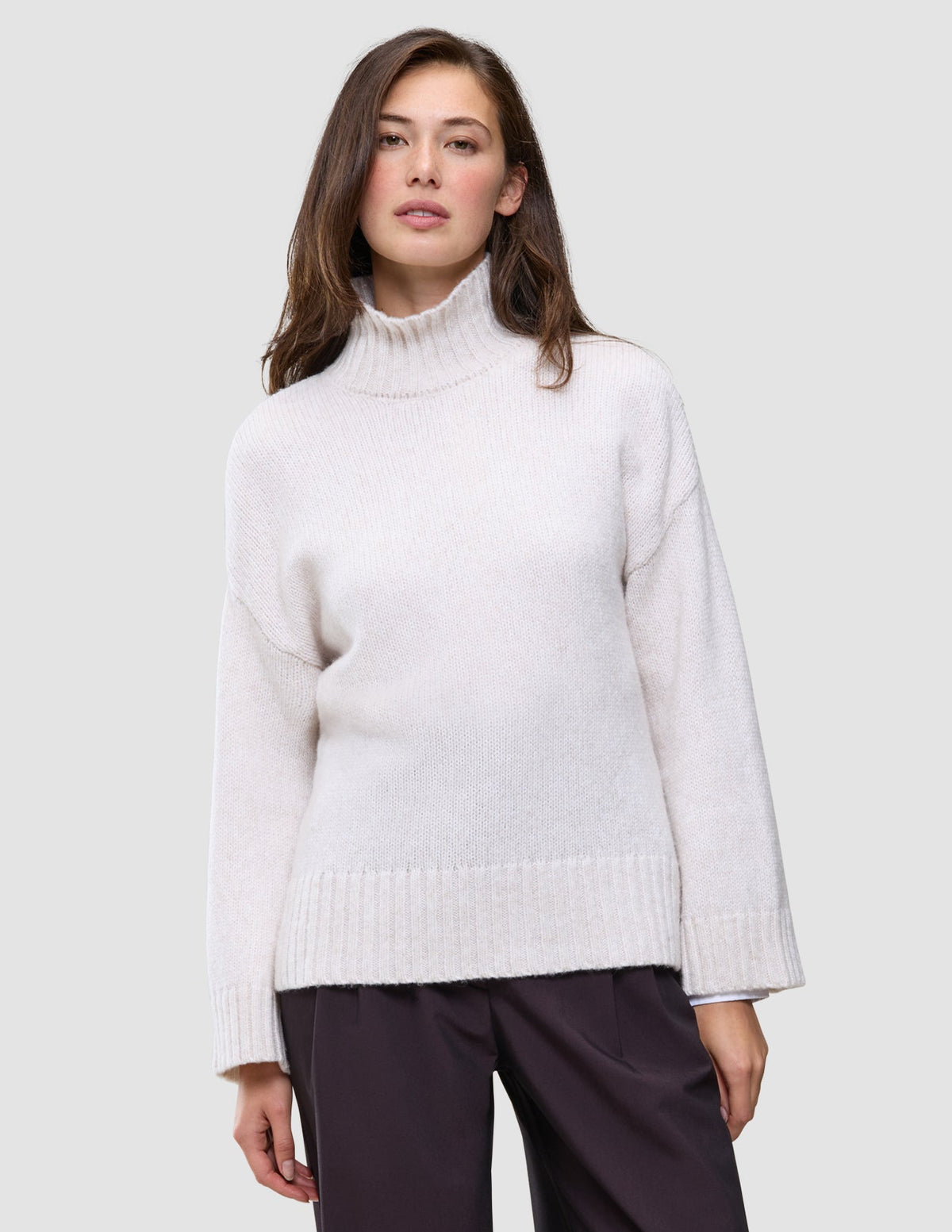 Frau in einem cremefarbenen, grob gestrickten Rollkragenpullover aus weicher Wolle: Damen-Rollkragenpullover aus grob gestrickter, weicher Wolle, Sugar Melange.