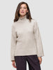 Eine Frau, die einen beigen Damen-Rollkragenpullover aus grobem, weichem Wollstrick in der Farbe Sugar Melange trägt, dazu eine dunkle Hose.