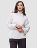 Eine Frau, die einen cremefarbenen Damen-Rollkragenpullover aus dickem, weichem Wollstrick in der Farbe Sugar Melange mit weiten Ärmeln trägt.