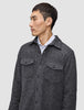 Ein Mann, der ein doppellagiges Woll-Overshirt in der Farbe Regular Dark Grey über einem Hemd mit Kragen trägt, das sich durch ein klares, skandinavisches Design auszeichnet.