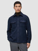 Eine Person, die ein doppellagiges Woll-Overshirt in der Farbe Regular Dark Navy über einem dunkelbraunen Rollkragenpullover trägt und damit klassisches skandinavisches Design zur Geltung bringt.