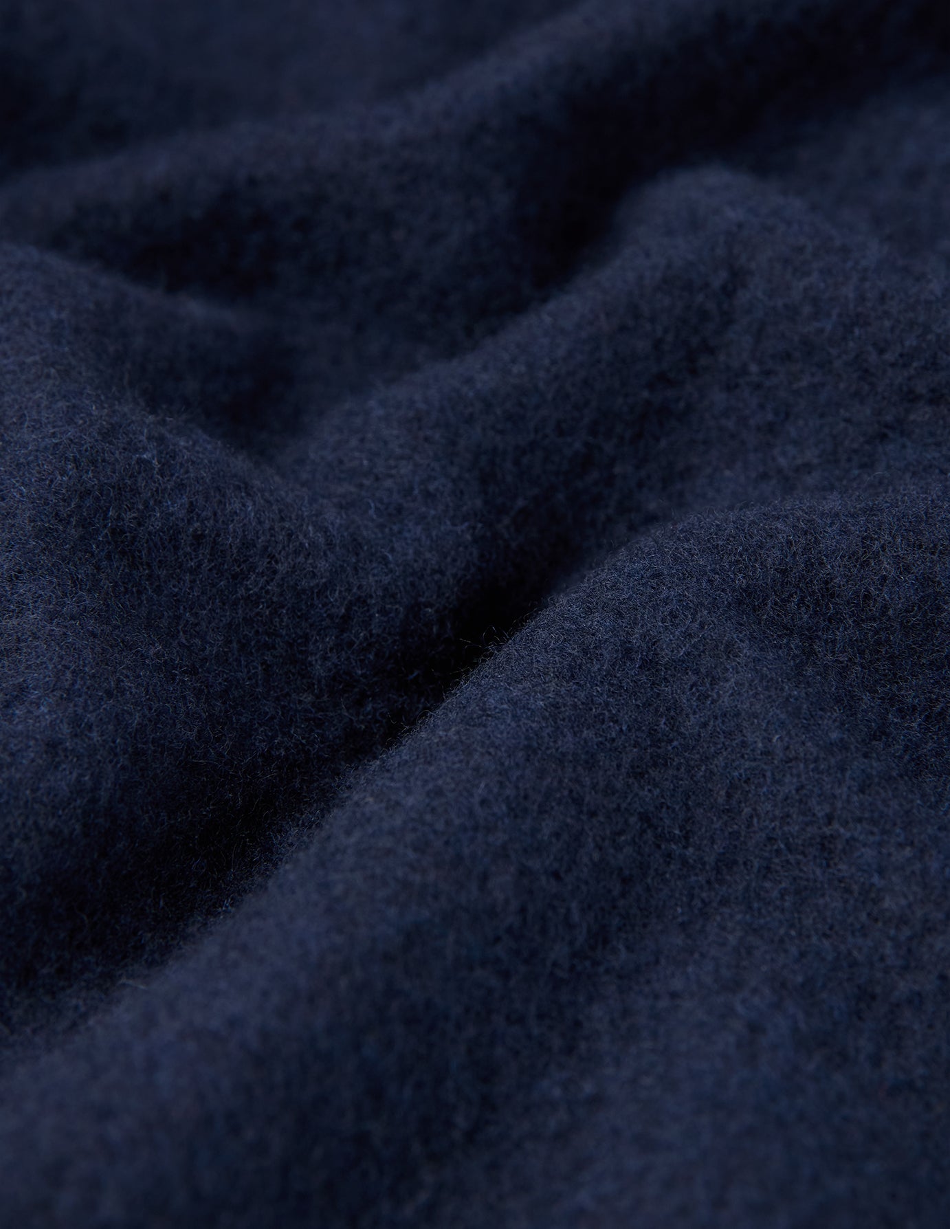 Nahaufnahme eines doppellagigen Woll-Overshirts in der Farbe Regular Dark Navy, die den marineblauen Stoff in tiefen, doppellagigen Falten zeigt.