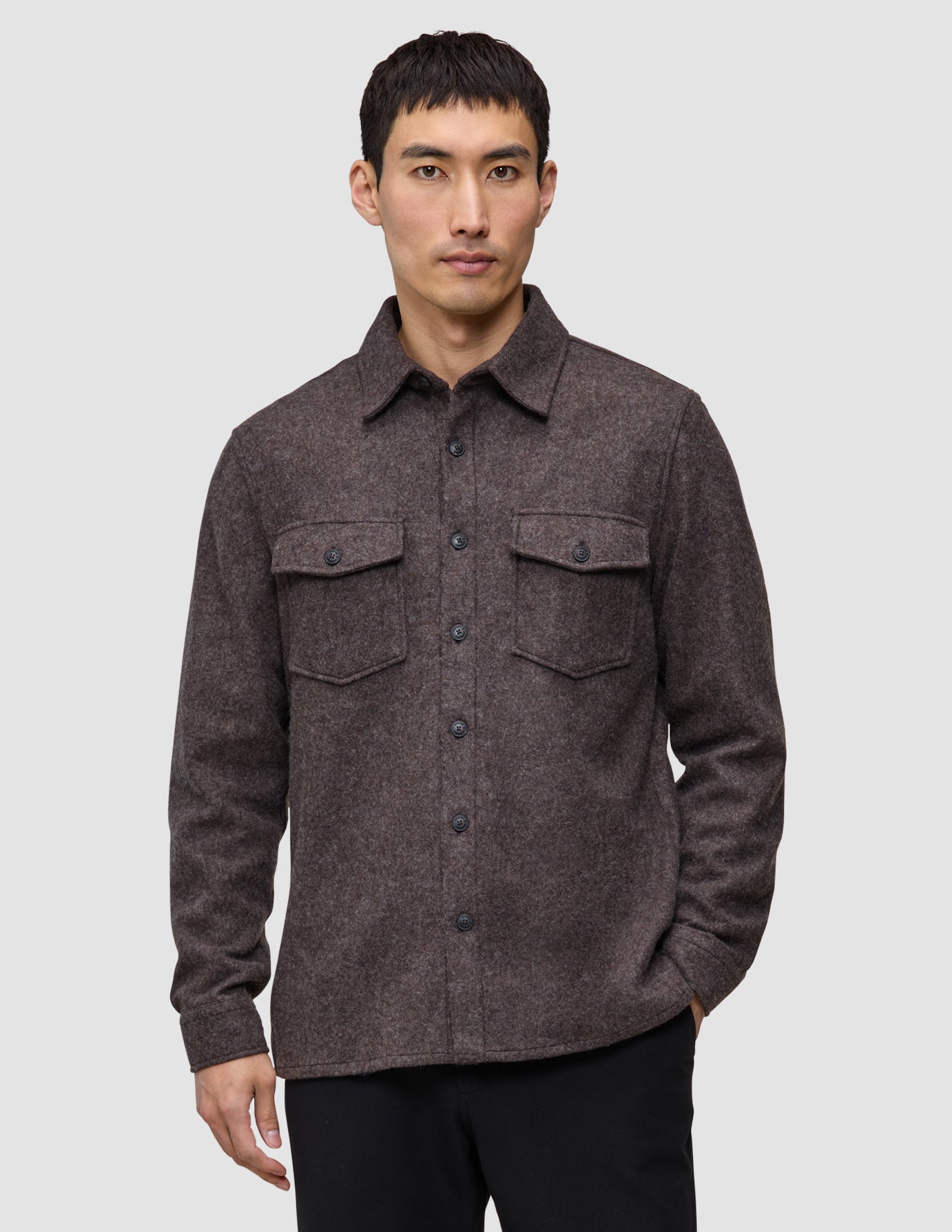 Ein Mann trägt ein doppellagiges Woll-Overshirt in Sattelbraun, das sich durch ein doppellagiges Design, zwei Brusttaschen und einen klassischen skandinavischen Stil auszeichnet.