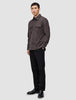 Eine Person, die ein doppellagiges Woll-Overshirt in Sattelbraun mit Brusttaschen, eine schwarze Hose und schwarze Loafer trägt.