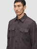 Ein Mann, der ein doppellagiges Woll-Overshirt in Sattelbraun trägt – ein braunes, doppellagiges Wollmodell mit zwei Brusttaschen, das im schlichten, skandinavischen Stil gefertigt ist.