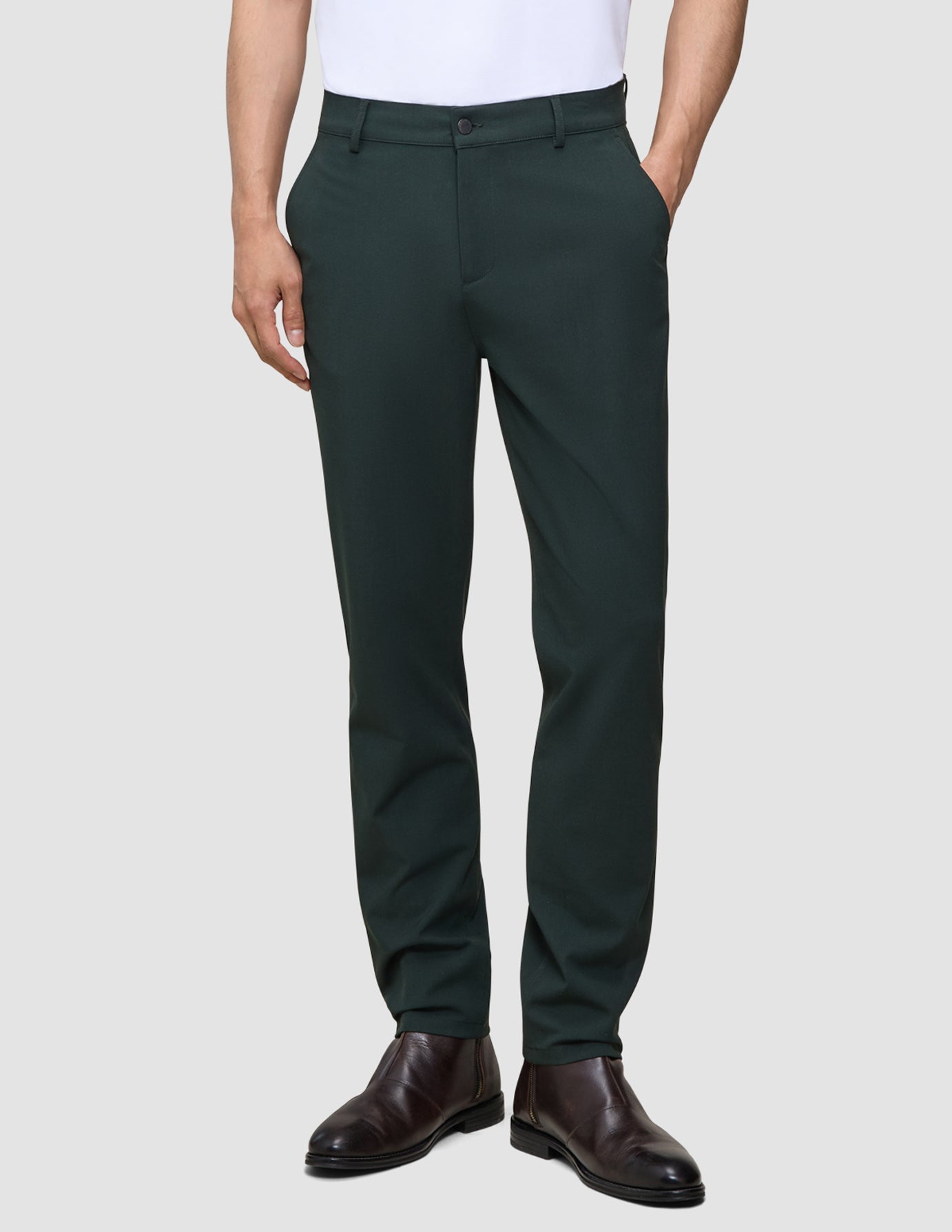 Eine Person, die eine dunkelgrüne Stretchhose Ease Pants Regular Northern Pine und dunkelbraune Lederstiefel trägt.