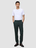 Ein Mann, der ein weißes T-Shirt und eine dunkelgrüne Ease-Hose Regular Northern Pine trägt und die Hände in den Taschen hat.