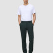 Ein Mann, der ein weißes T-Shirt und eine dunkelgrüne Ease-Hose Regular Northern Pine trägt und die Hände in den Taschen hat.