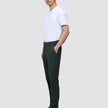 Eine Person trägt eine Ease Pants Regular Northern Pine und ein weißes T-Shirt und steht im Profil, wobei sie eine Hand in der Tasche hat.