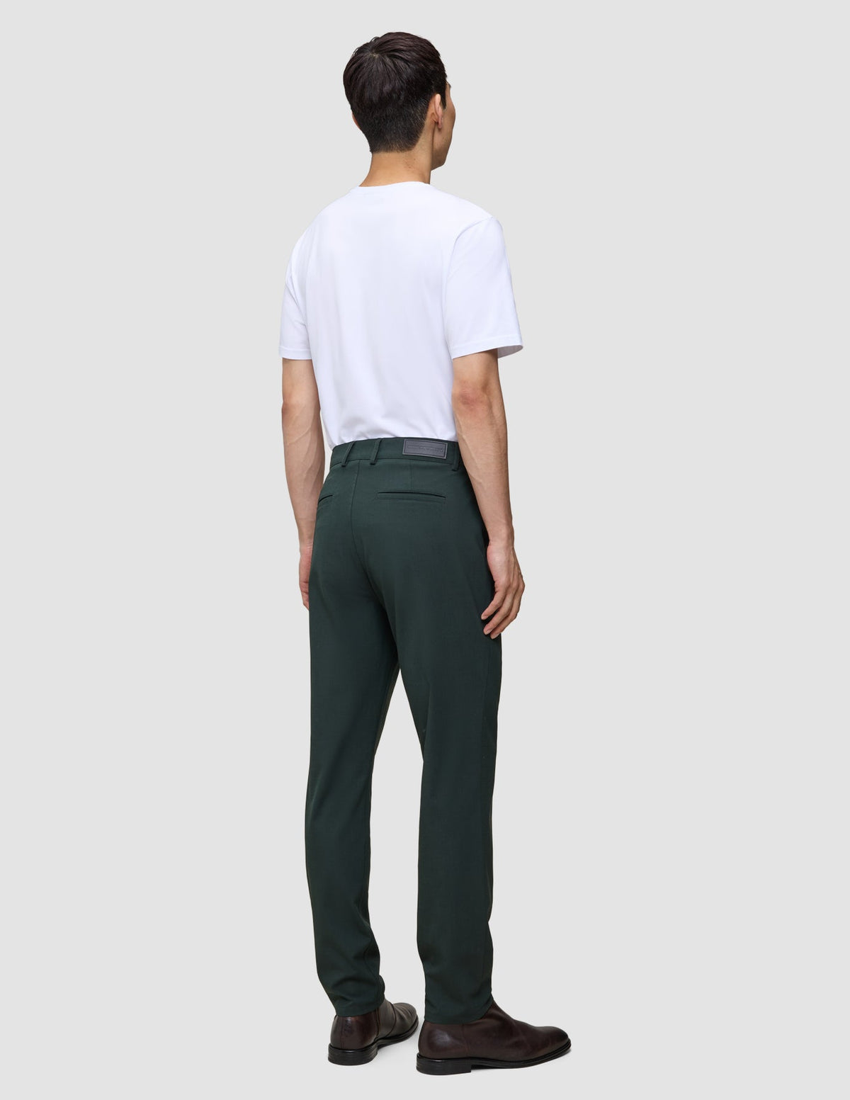Eine Person, von hinten gesehen, die ein weißes T-Shirt und eine bequeme dunkelgrüne Ease-Hose Regular Northern Pine trägt.