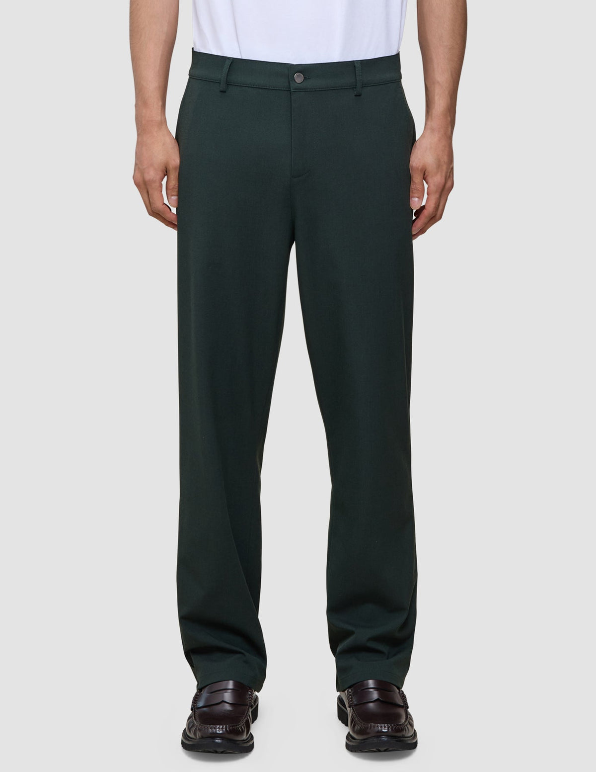 Person, die eine Ease Pants Relaxed Fit Northern Pine in lockerer Passform mit braunen Loafern trägt; die Hose verfügt über 360°-Stretch.